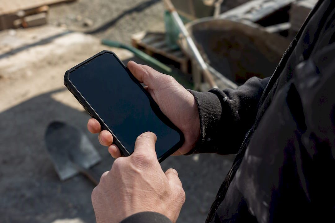 Tradesperson hands answering phone call outdoors