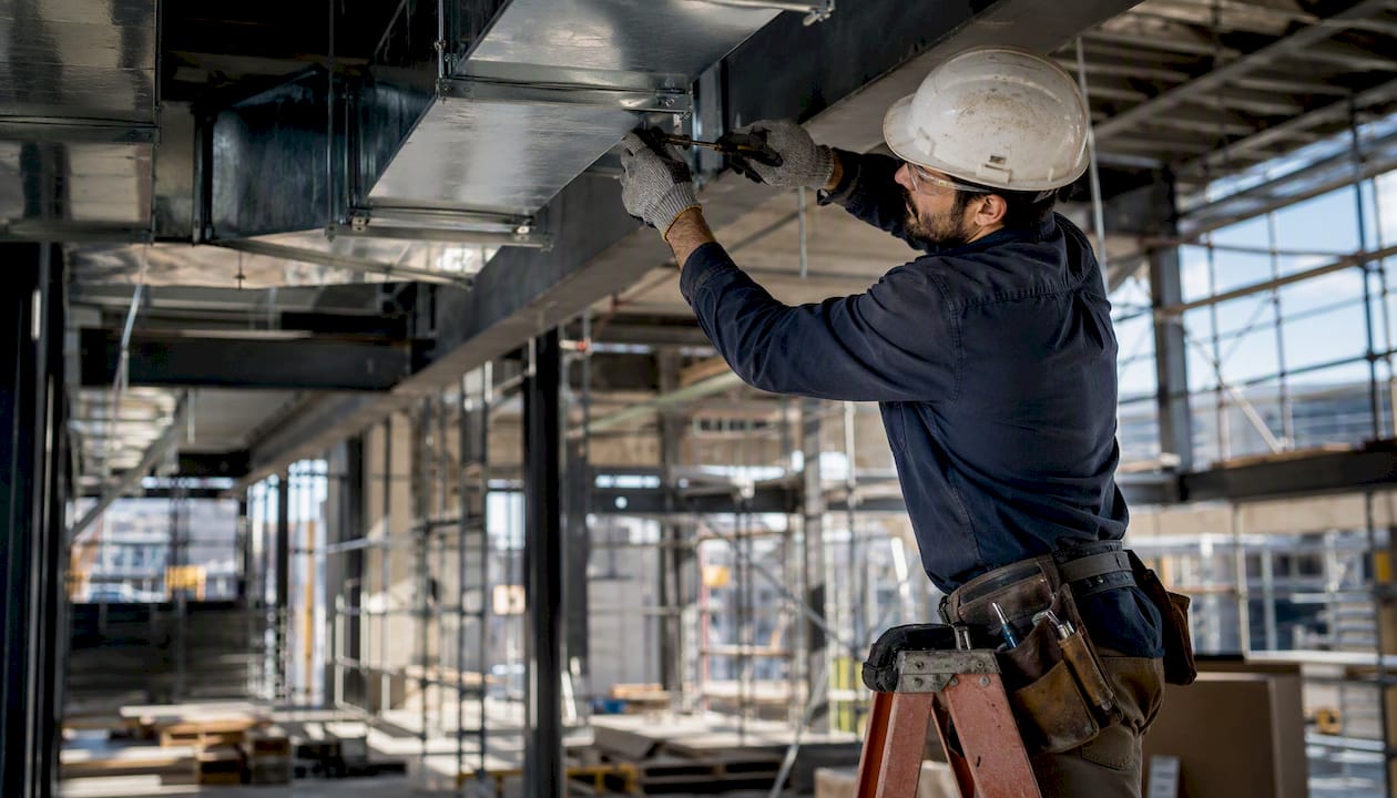 Sheet metal worker installing HVAC ductwork