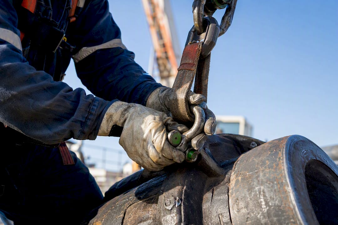 Hands securing rigging sling in industrial setting