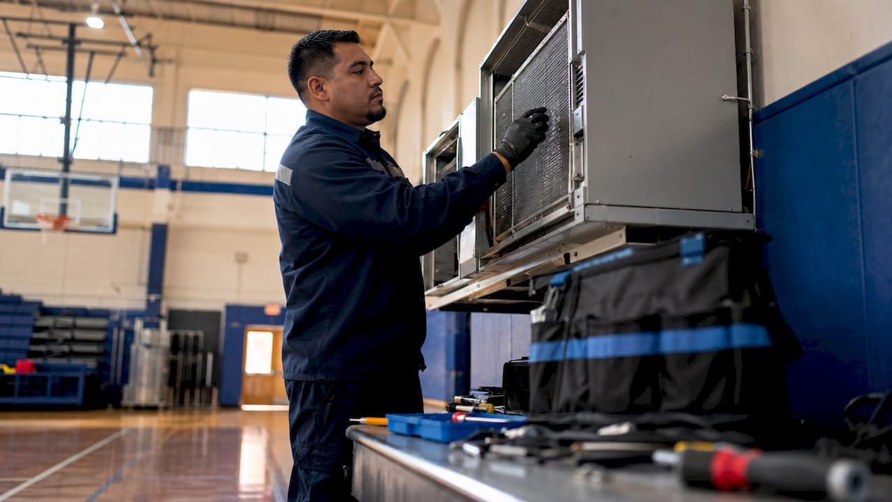 Technician inspecting school HVAC unit