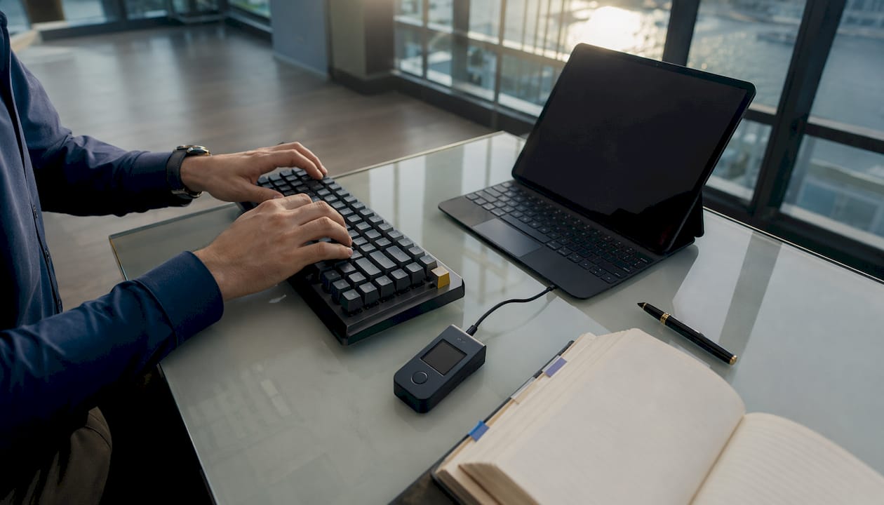 Close-up hands at keyboard with crypto hardware wallet