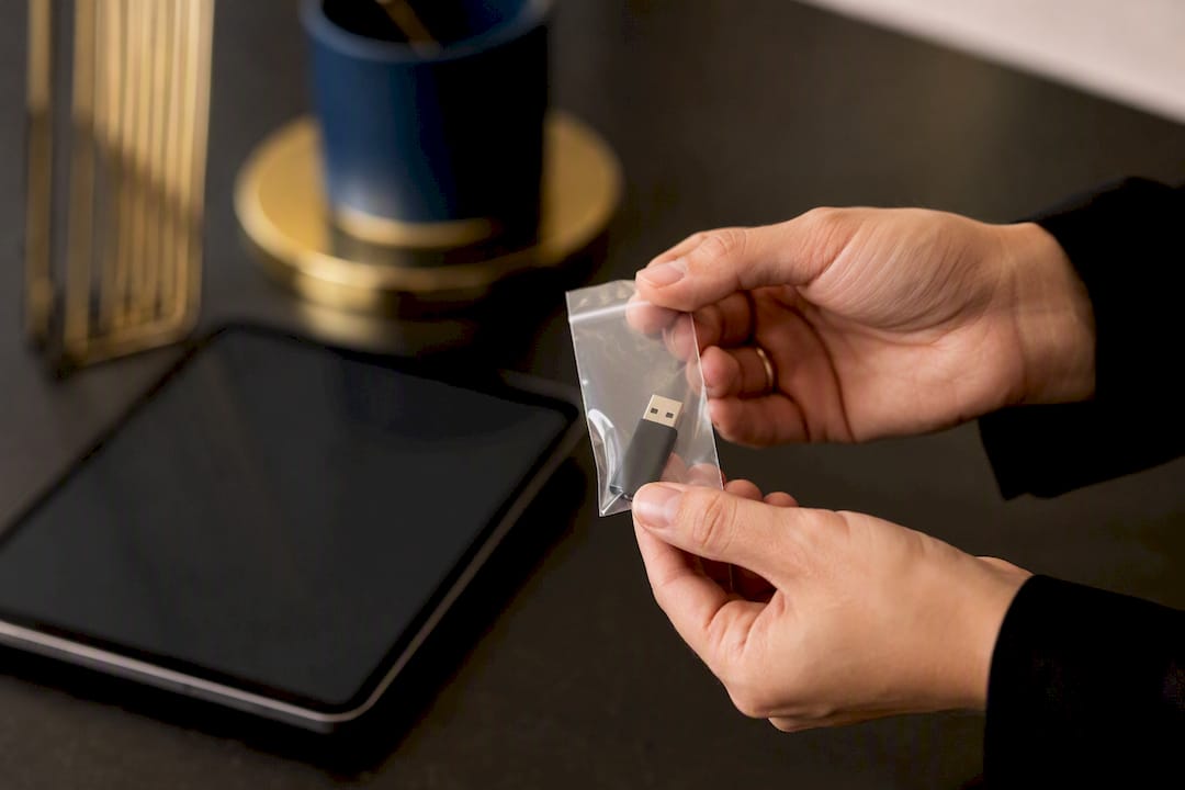 Hands holding evidence bag with USB drive for blockchain export