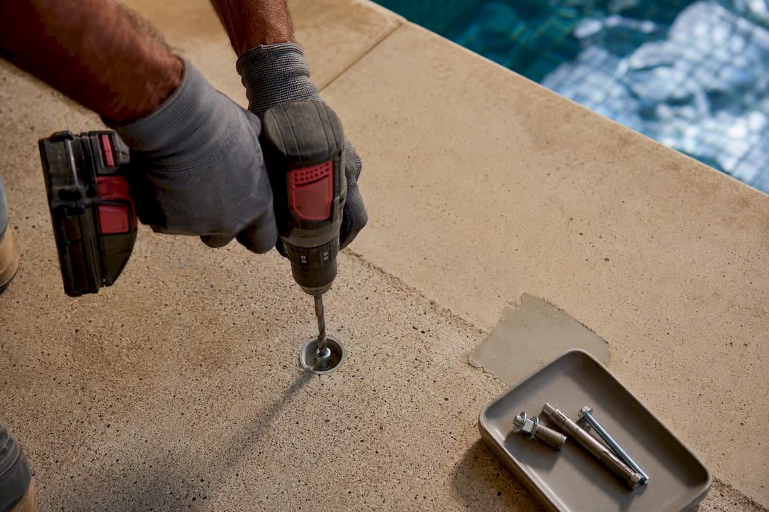 Technician drilling a pool cover anchor point