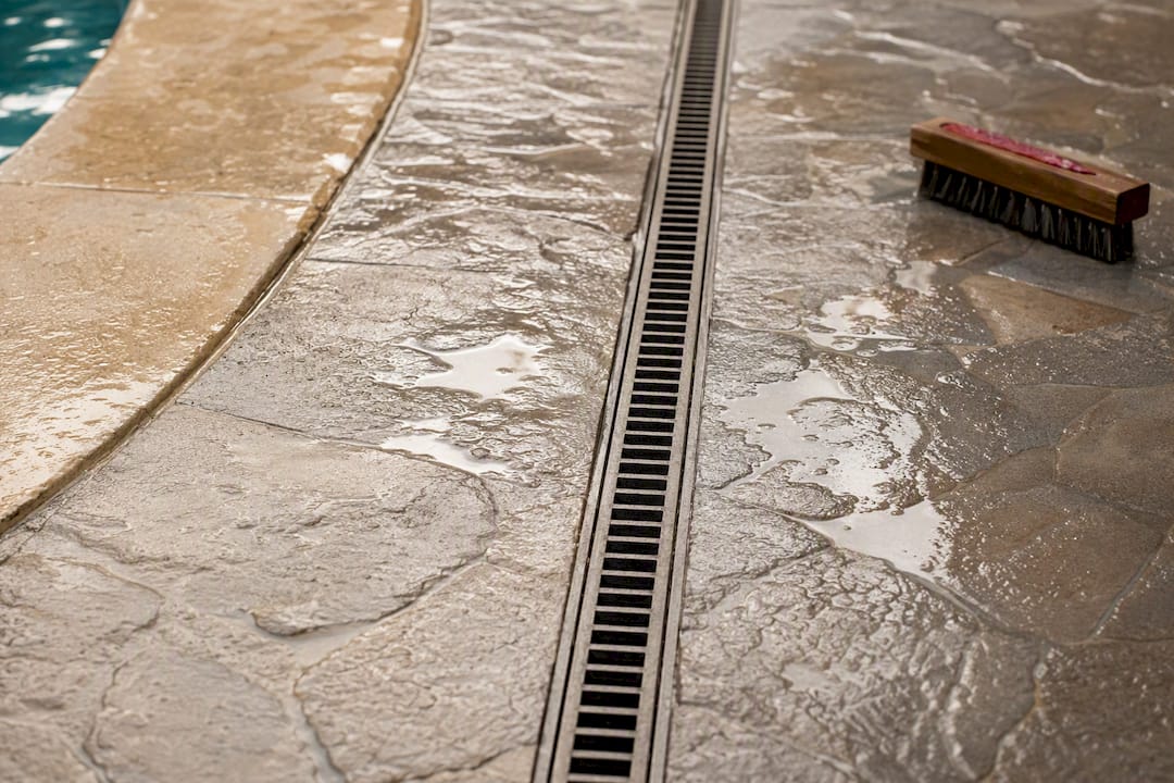 Flush narrow-slot grate in wet pool paving