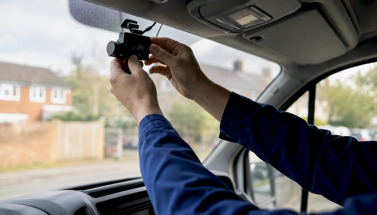 Hands installing dash cam inside vehicle
