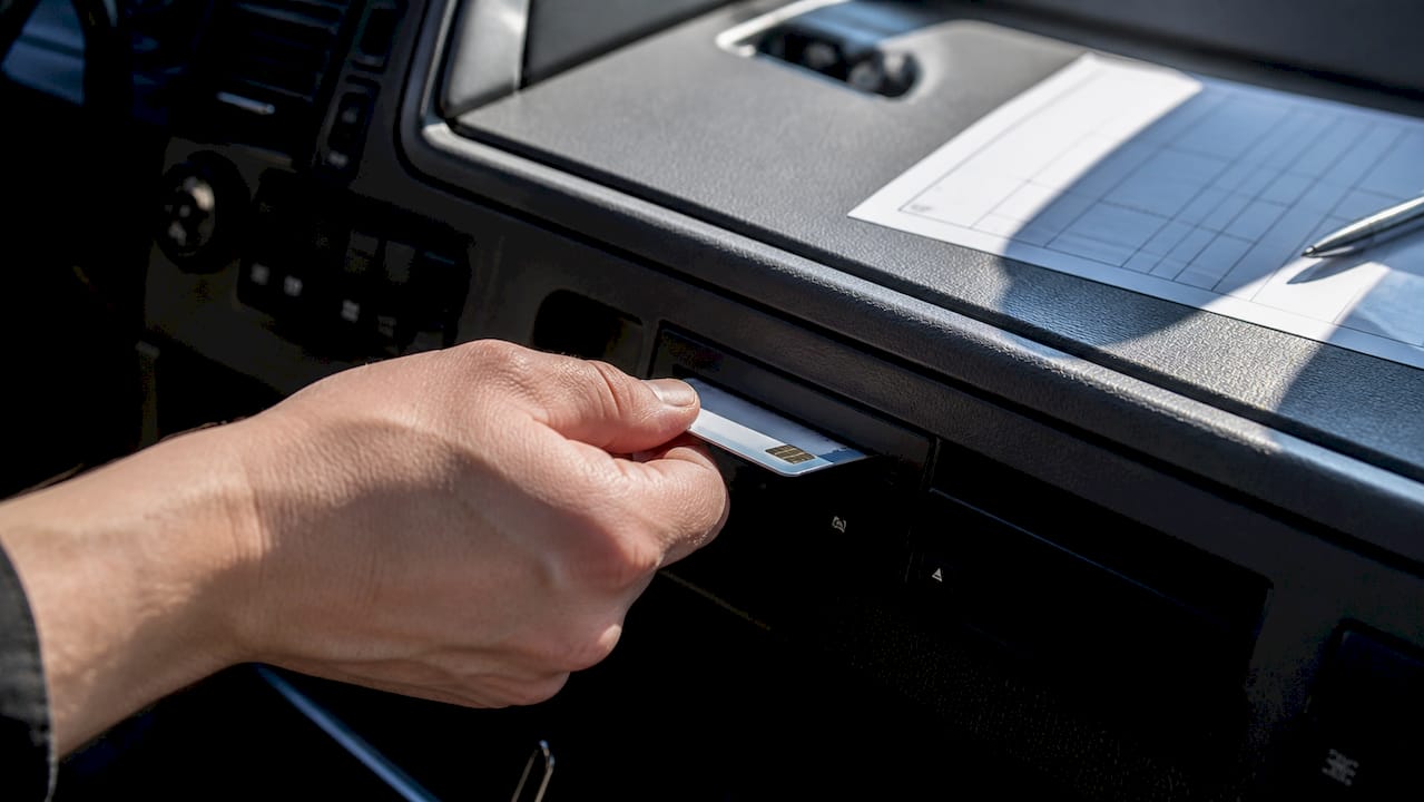 Driver holding tachograph card inside truck cab