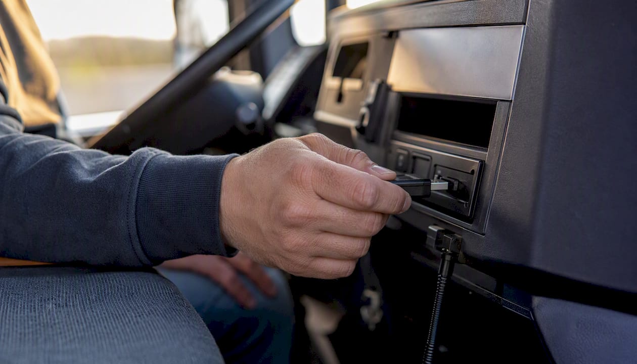 Hands plugging USB into truck tachograph device