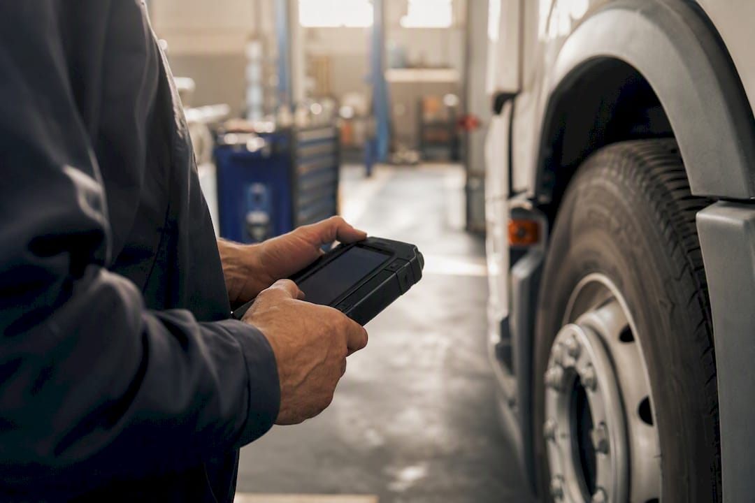 Technician using device near vehicle wheel arch