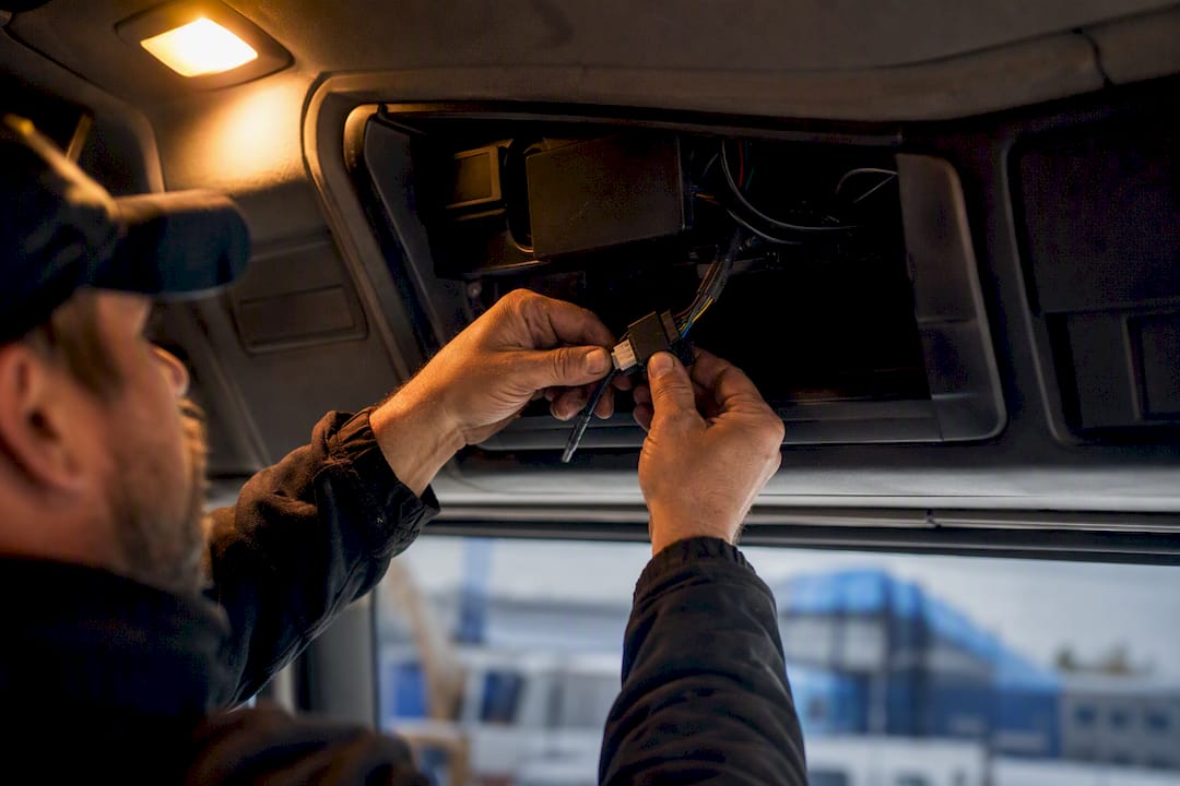 Hands connecting telematics device in truck cabin