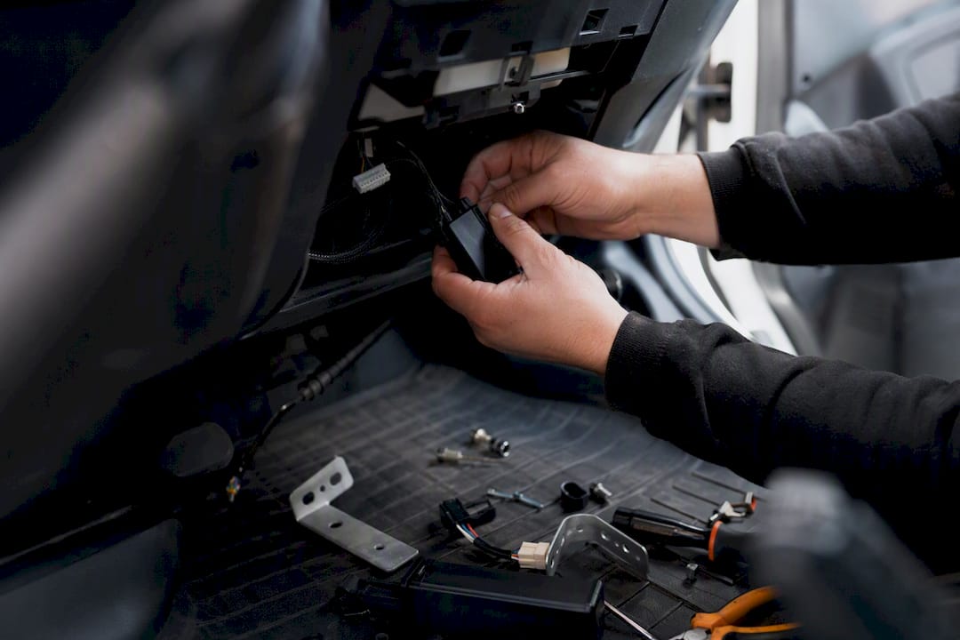 Hands installing telematics device in vehicle cab