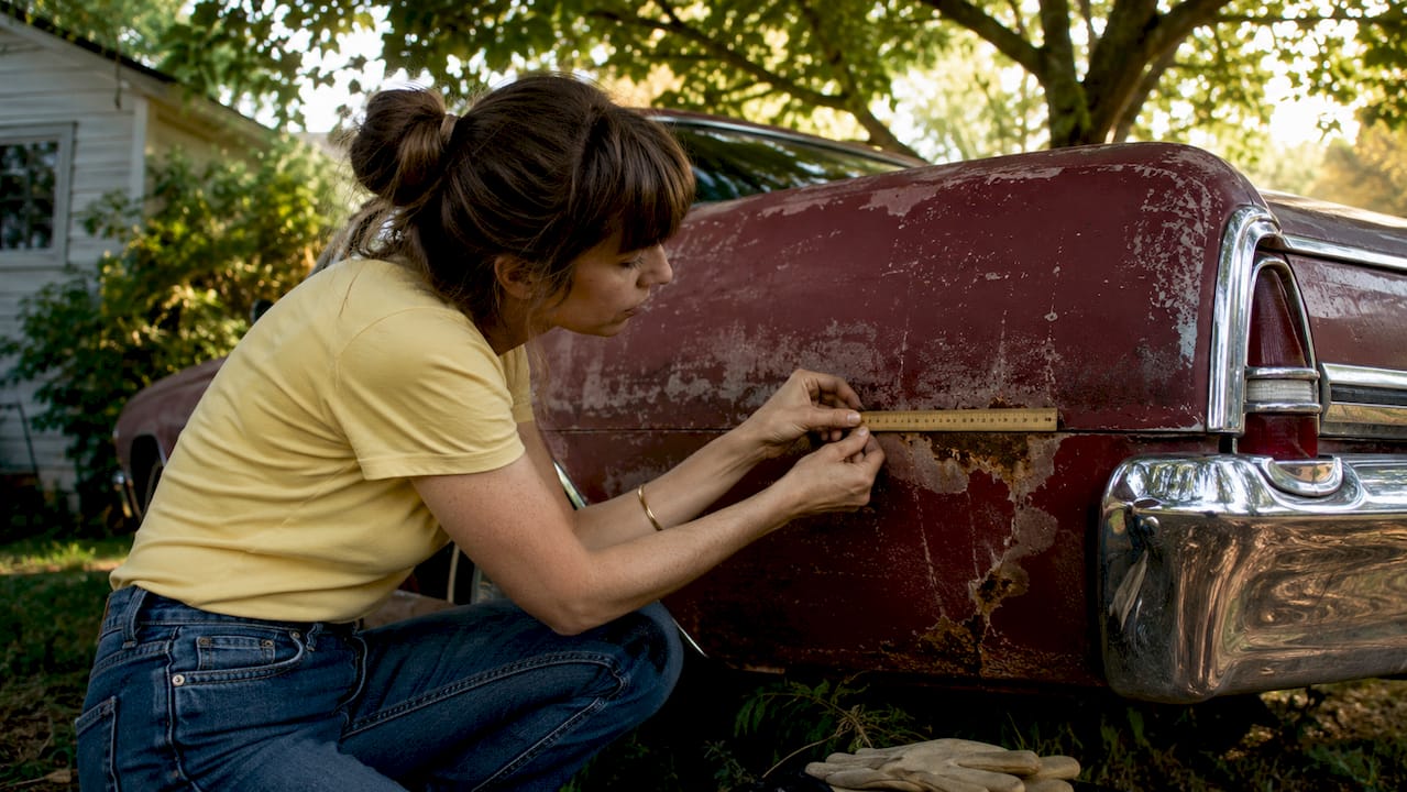 Hands testing vintage car body with magnet