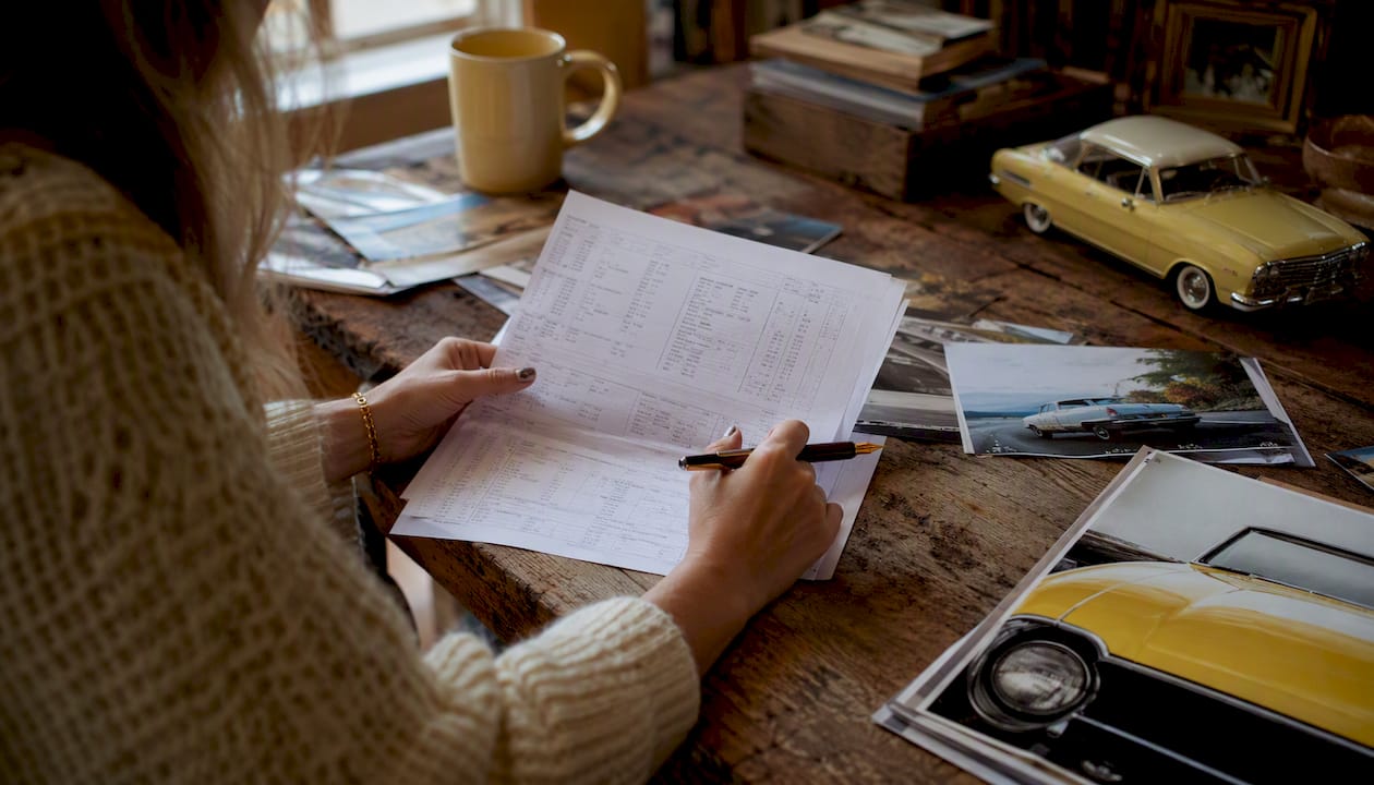 Hands reviewing vehicle history reports on desk