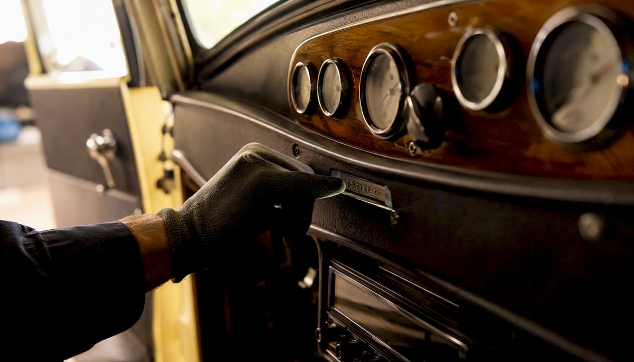 Hand pointing at VIN on vintage car dashboard