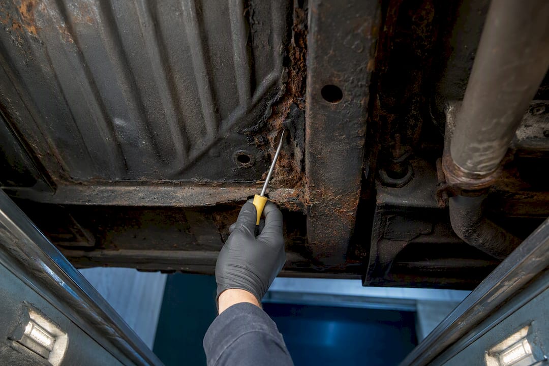 Inspector probing rusted frame rail seam