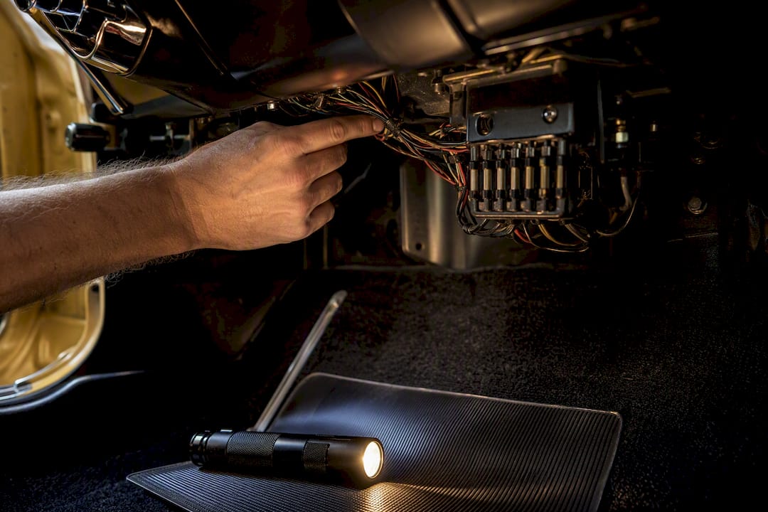 Inspecting vintage car wiring beneath dashboard