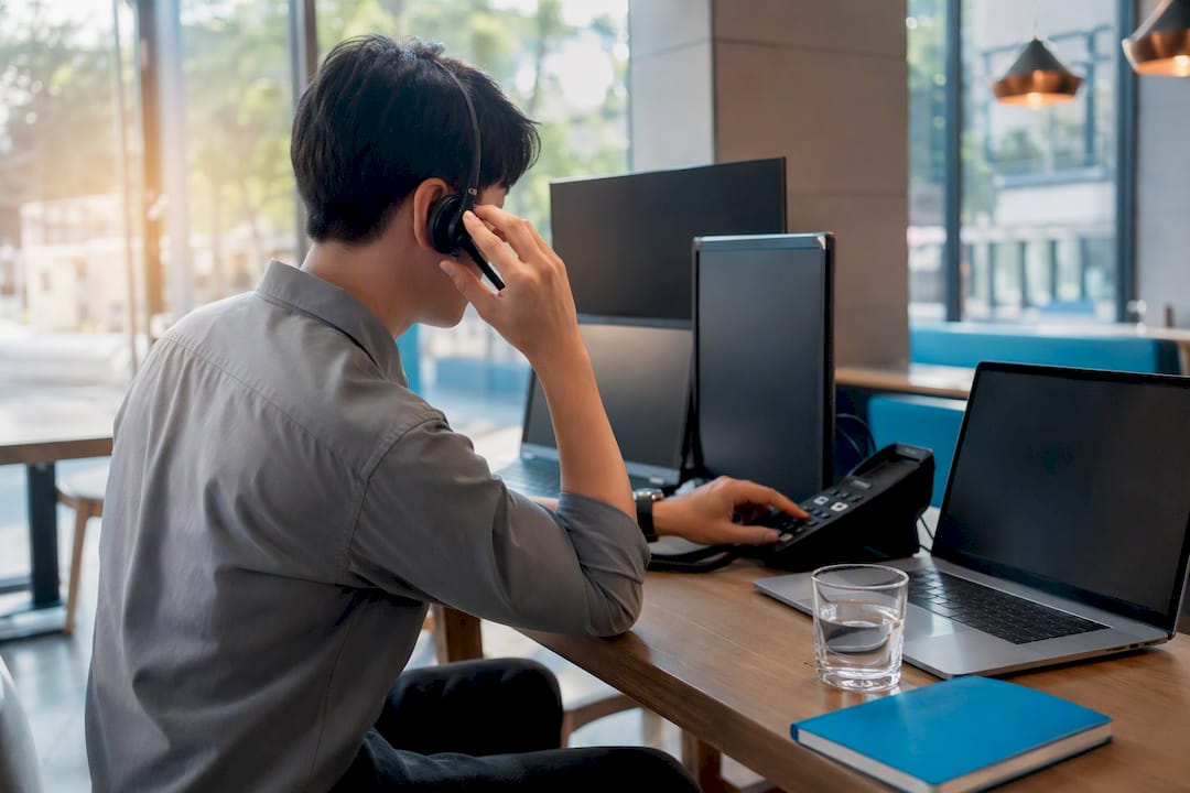 Support agent adjusting headset at desk