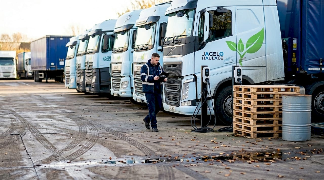 Line of HGVs in depot yard, EV chargers visible