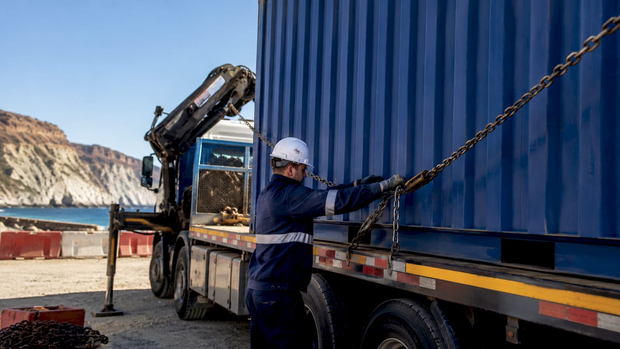 Driver securing container for Hiab crane offloading