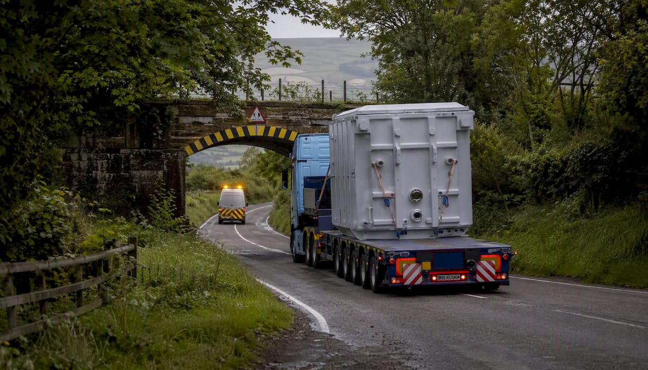 Abnormal load transport passing low bridge with escort