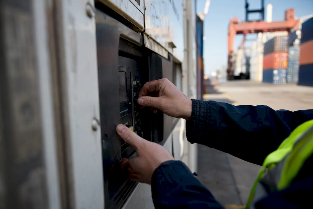 Hands adjusting reefer container temperature