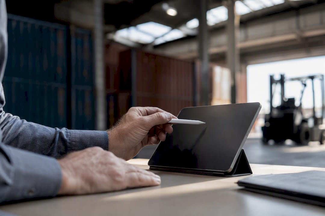 Hands pointing at tablet in container warehouse negotiation