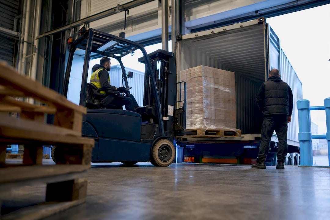 Forklift unloading container at warehouse dock