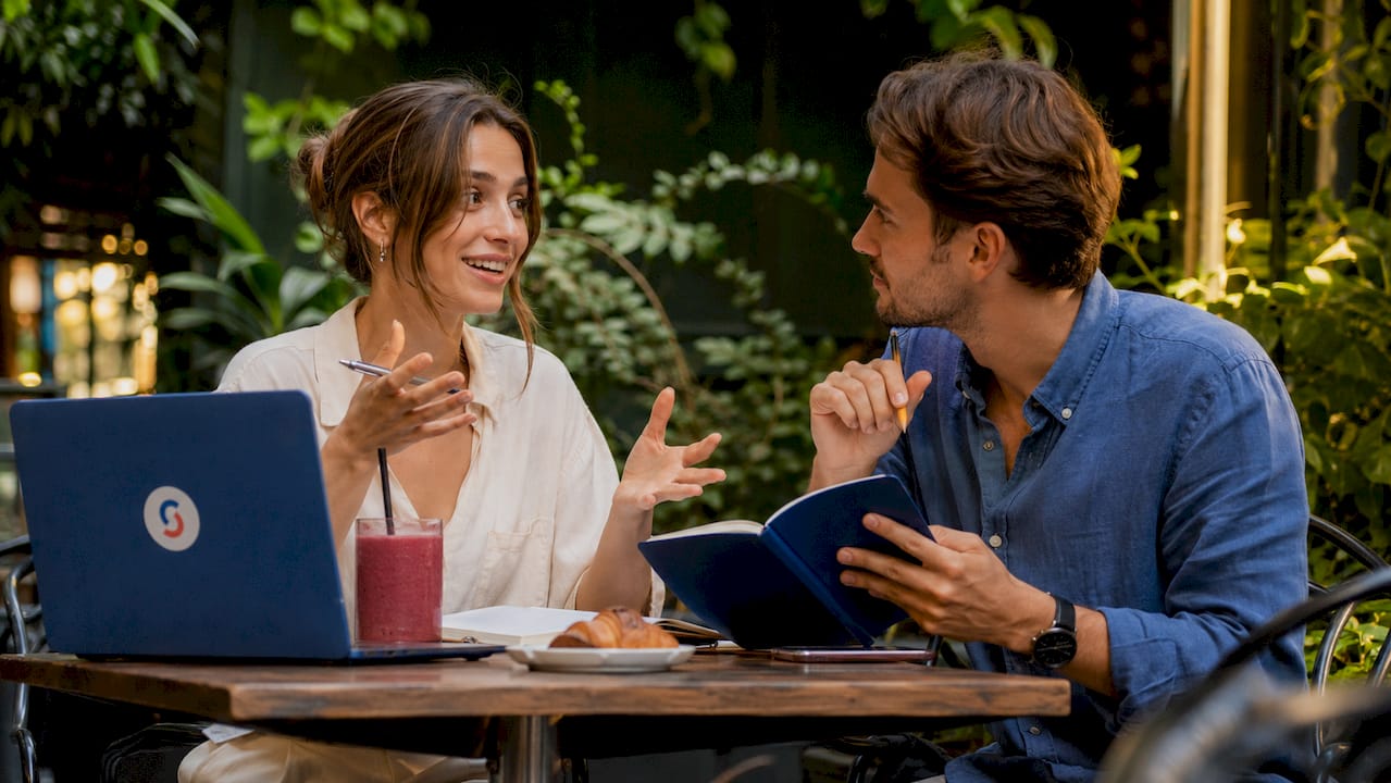 Tutor and student practicing language conversation at cafe table