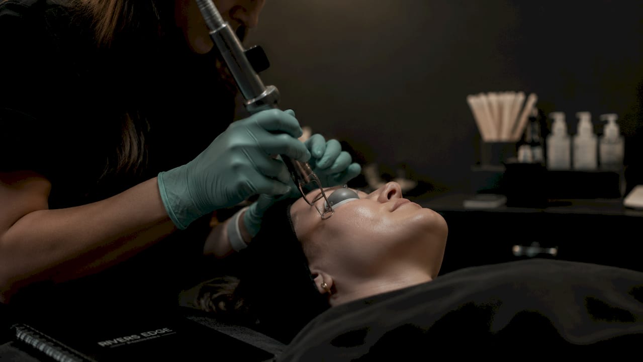 Close-up hands holding laser on patient's cheek