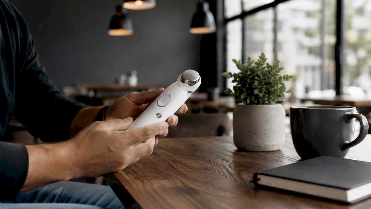 Close-up of ultrasound skincare device and hands