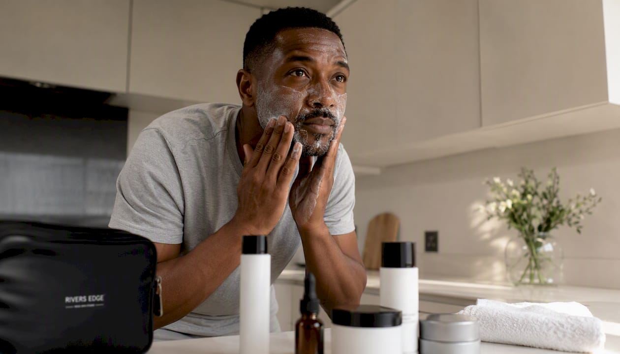 Man applying cleanser in bright bedroom