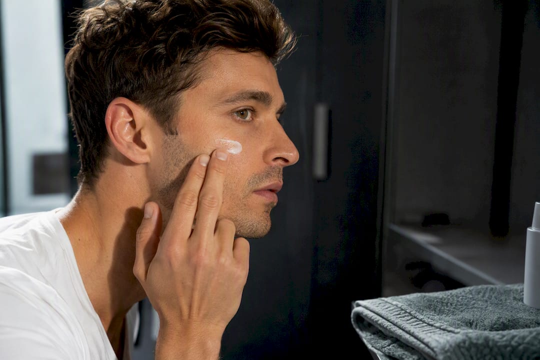 Man applying lightweight sunscreen to cheek