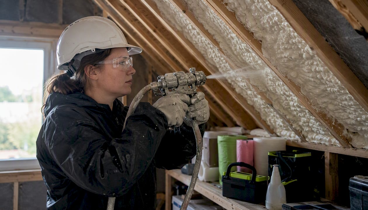 Installer applying closed-cell foam in UK home attic