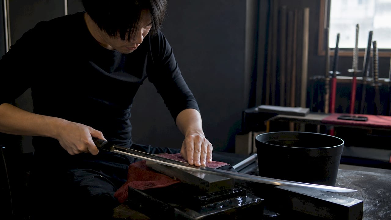 Artisan sharpening hand-forged katana blade up close