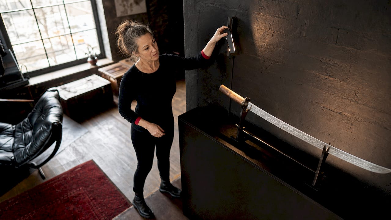 Collector adjusting LED spotlight on sword display