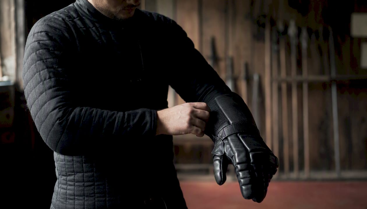 Hand adjusting fit of protective training glove