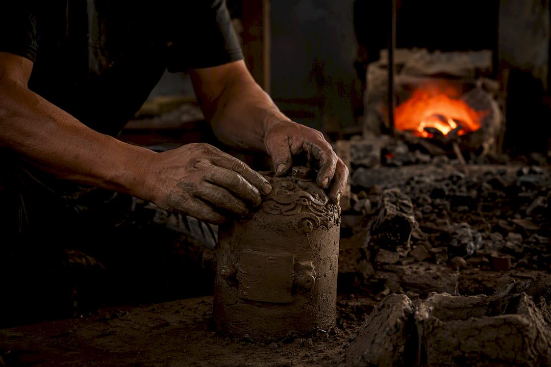 Hands preparing lost-wax bronze mold for casting