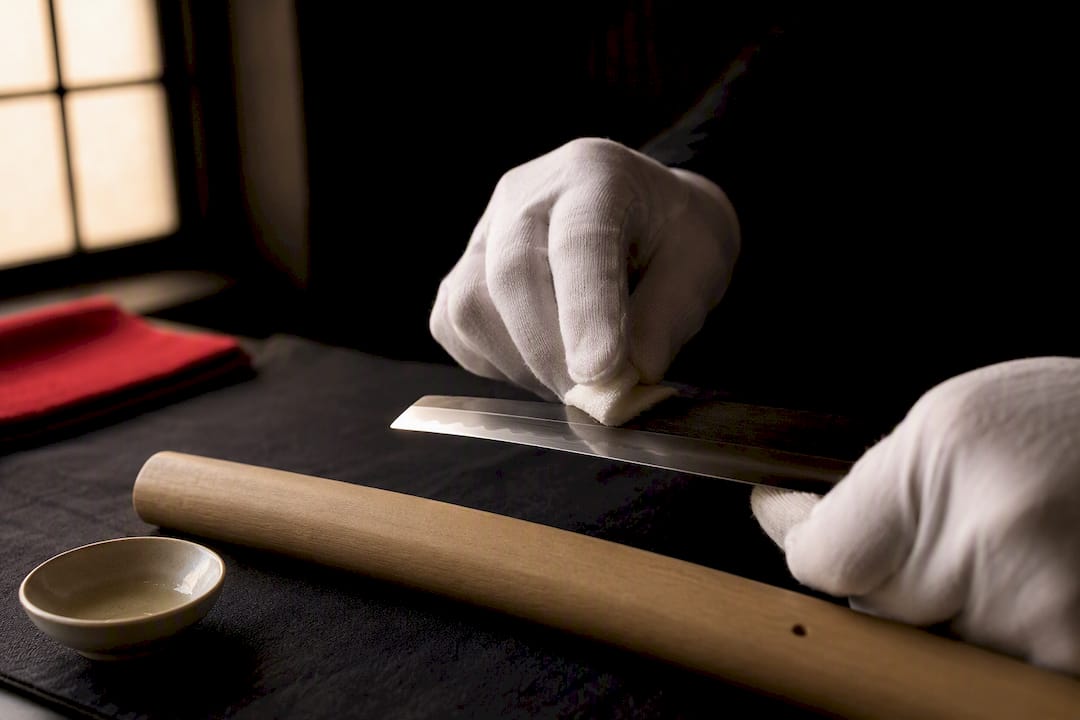 Gloved hands oiling a blade for storage