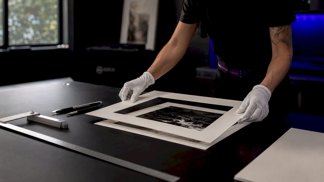 Hands placing archival mat board on limited edition print