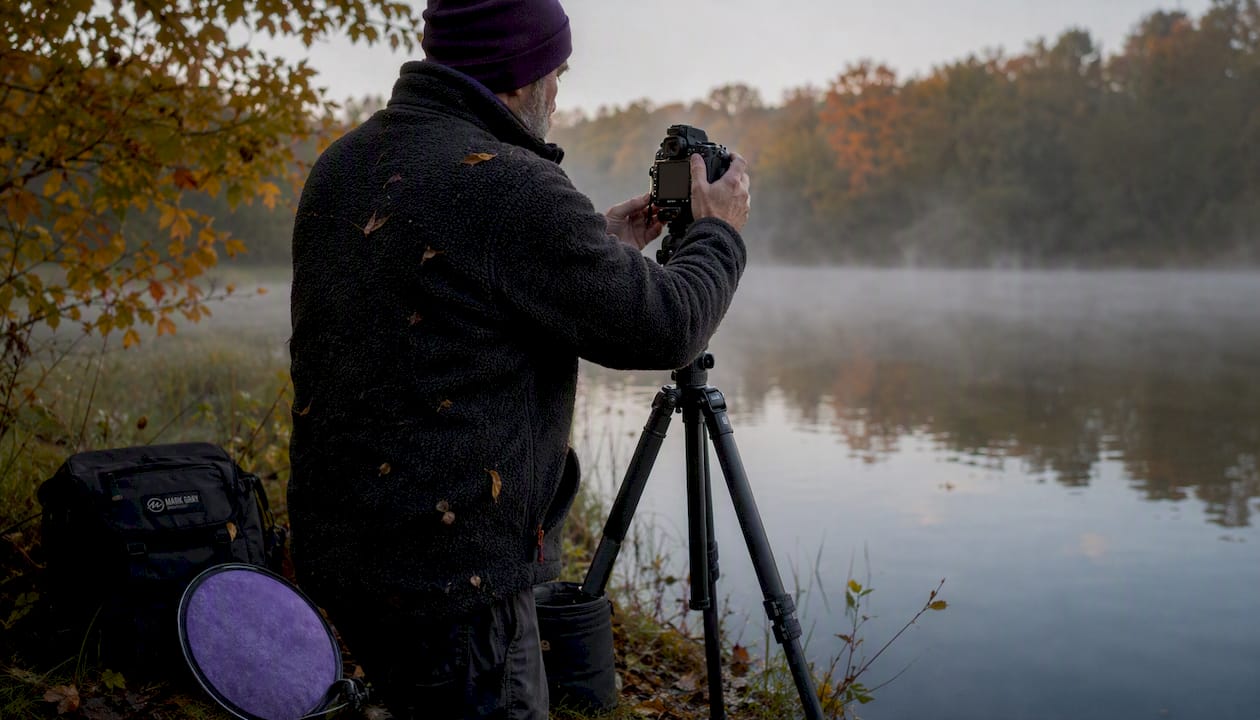 Photographer adjusting camera for vertical shot outdoors