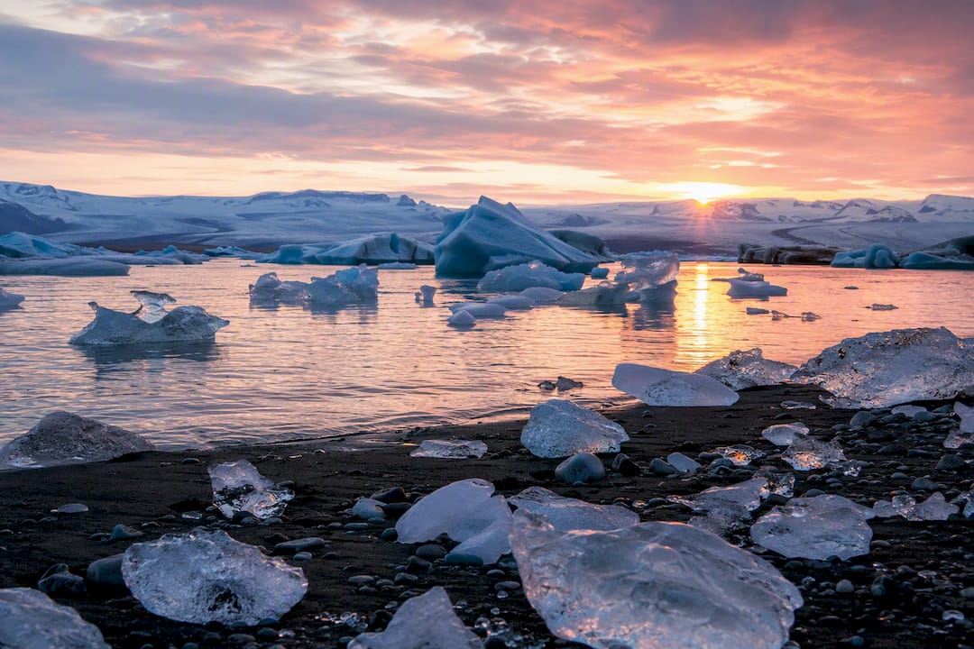 Sunrise over iceberg lagoon and ice-strewn black sand beach