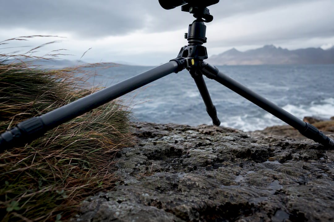 Low tripod braced against coastal wind