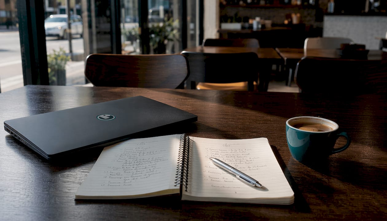 Laptop and notebook with strategy notes on wood desk
