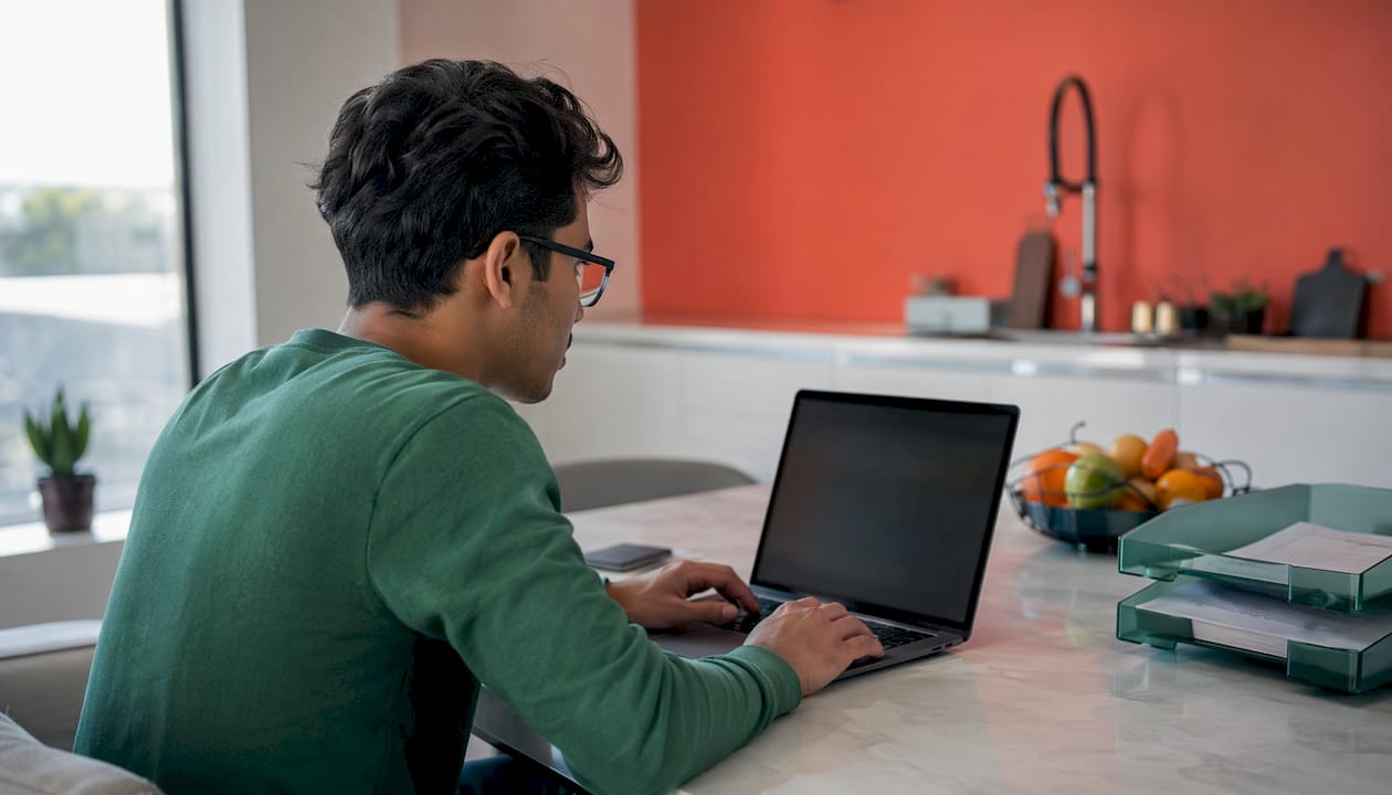 Student using laptop for digital question bank in home office
