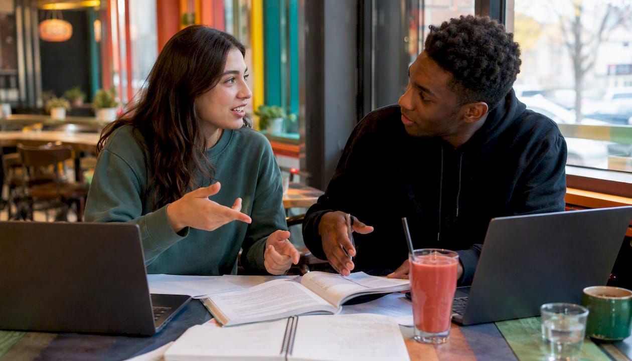 Two students reviewing test prep materials in library