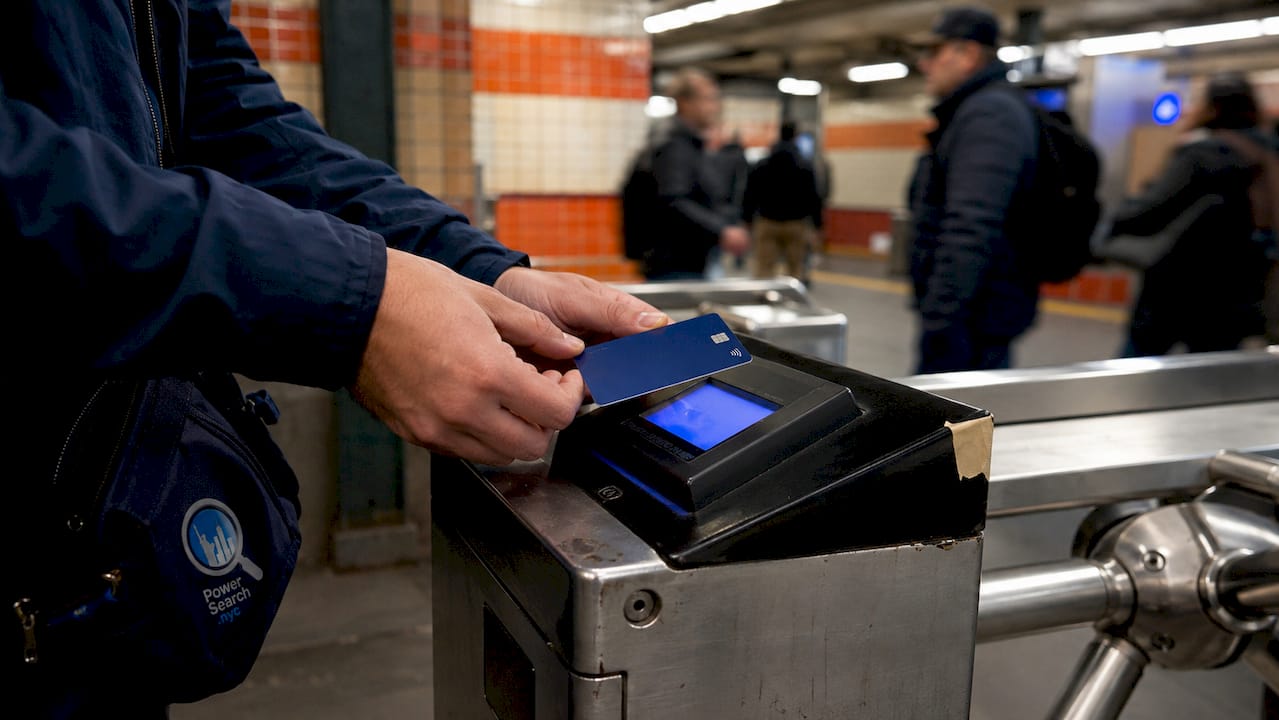 Hands tapping contactless card on OMNY transit reader