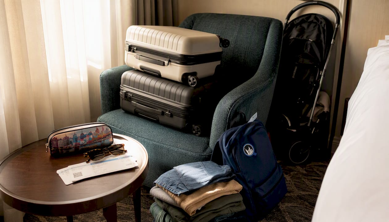 Two carry-on suitcases with family travel gear on bed