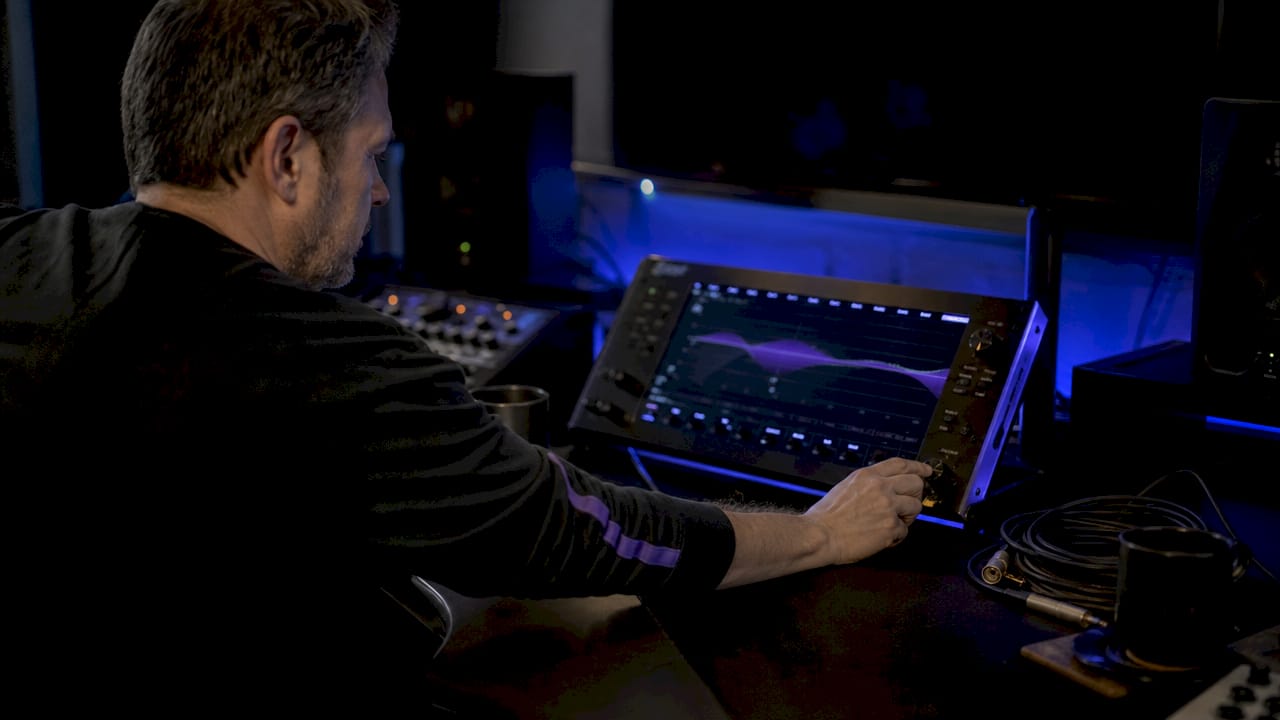 Hands adjusting parametric EQ frequency knob on monitor