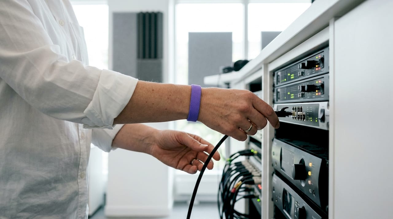 Technician connecting Ethernet cable to digital audio rack