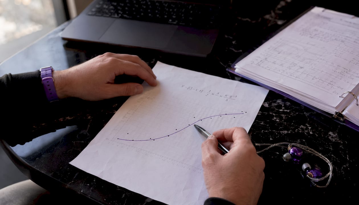 Hands pointing at SNR formula graph on desk