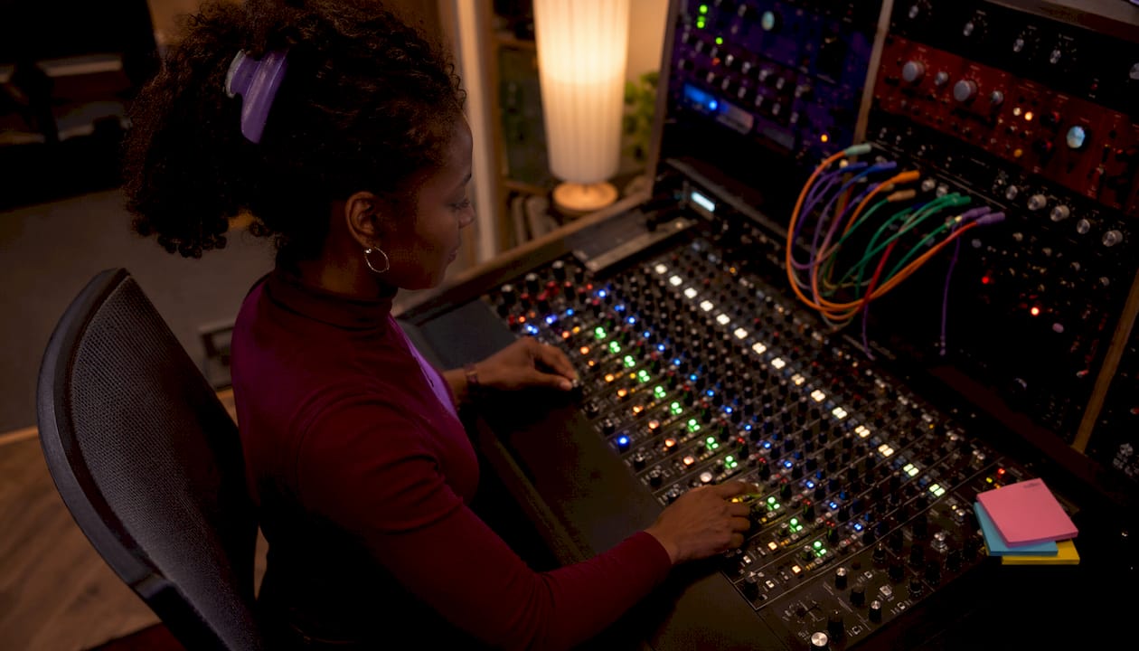Hands adjusting audio mixer routing controls in studio
